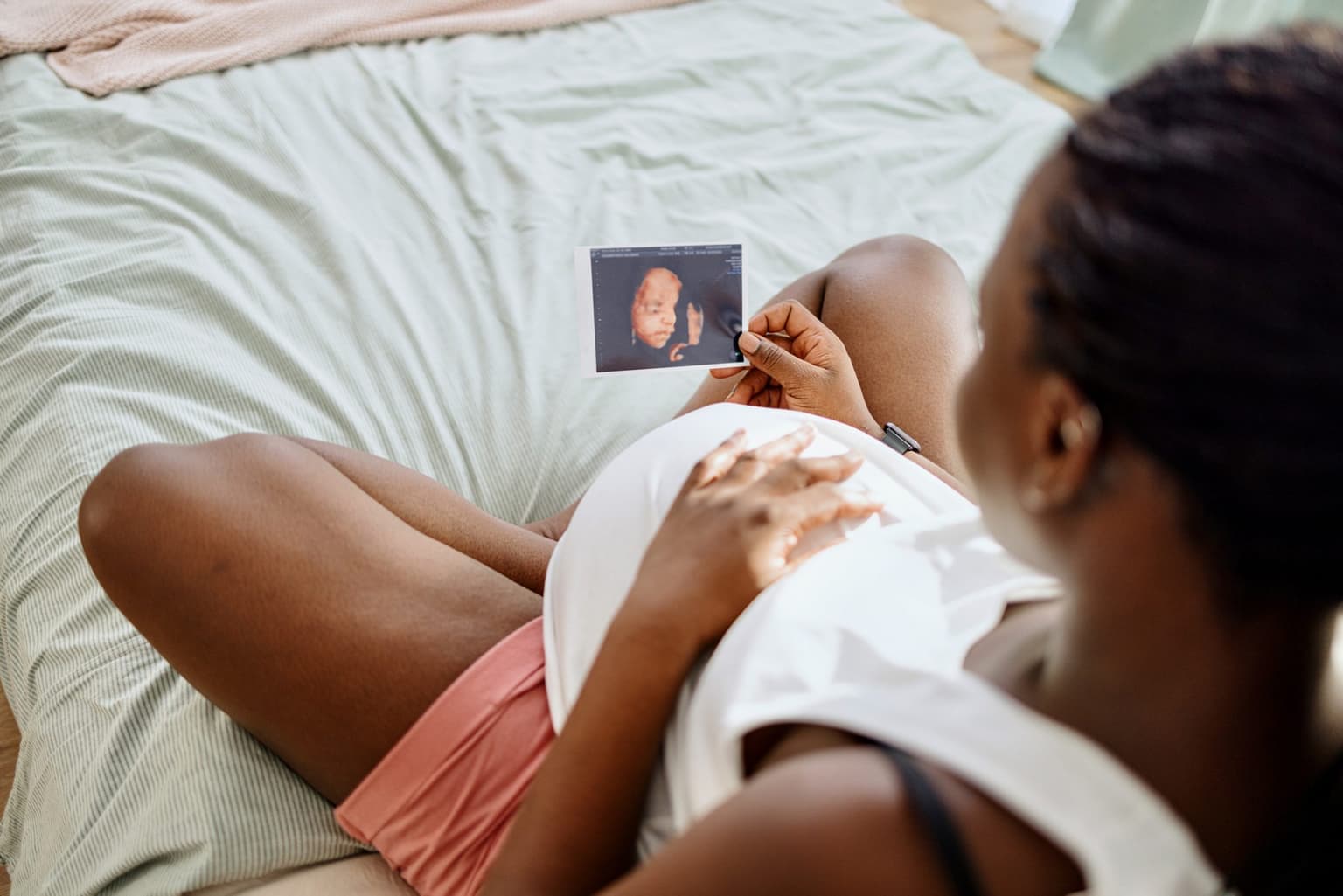 Pregnant woman gazing at ultrasound picture of her baby